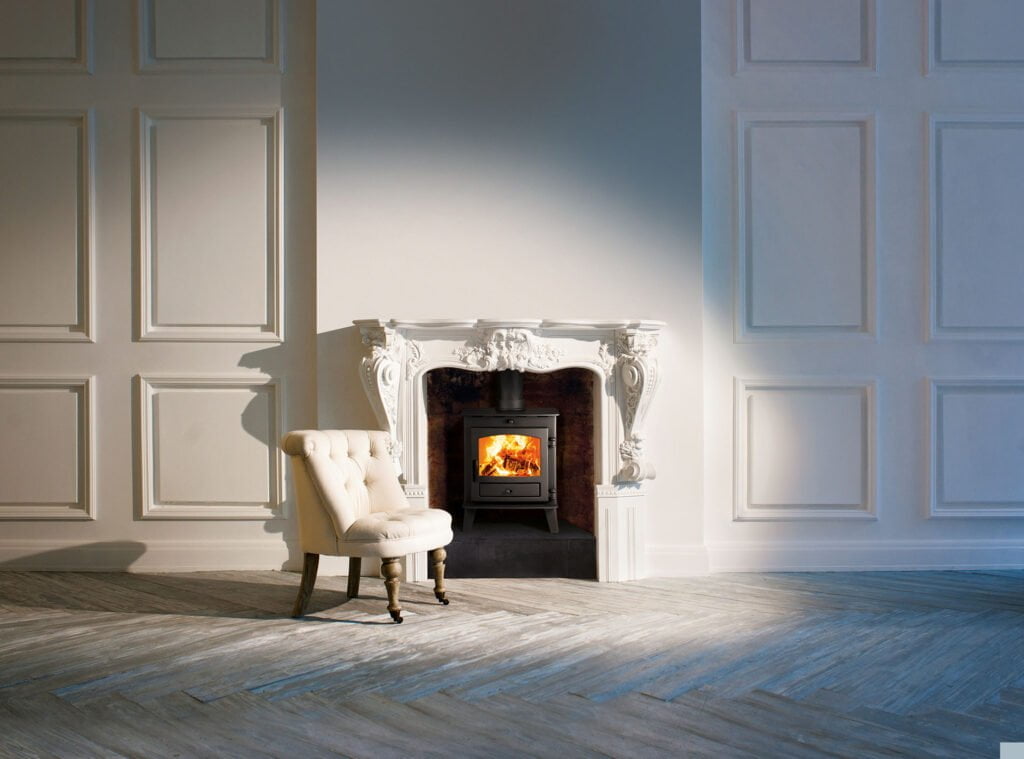 Chair in front of ornate white stone fireplace. BWF Humphries Stonemasons, Wood Burning Stoves, Granite Worktops, Quartz Worktops. Hungerford, Newbury, Marlborough.